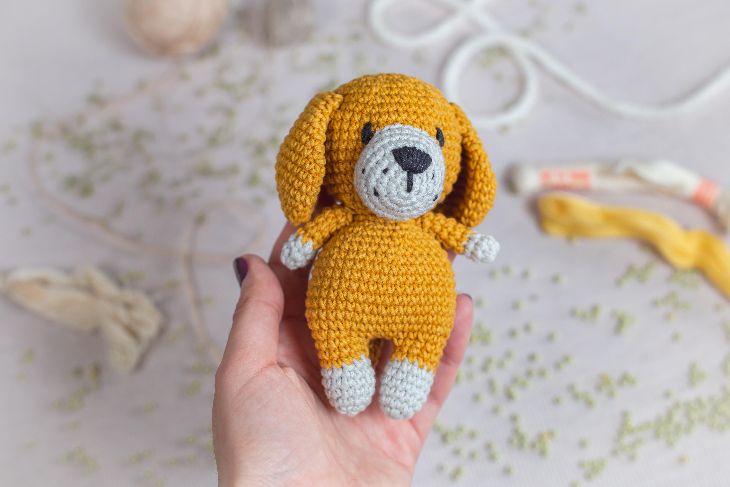 a hand holding a small crocheted dog